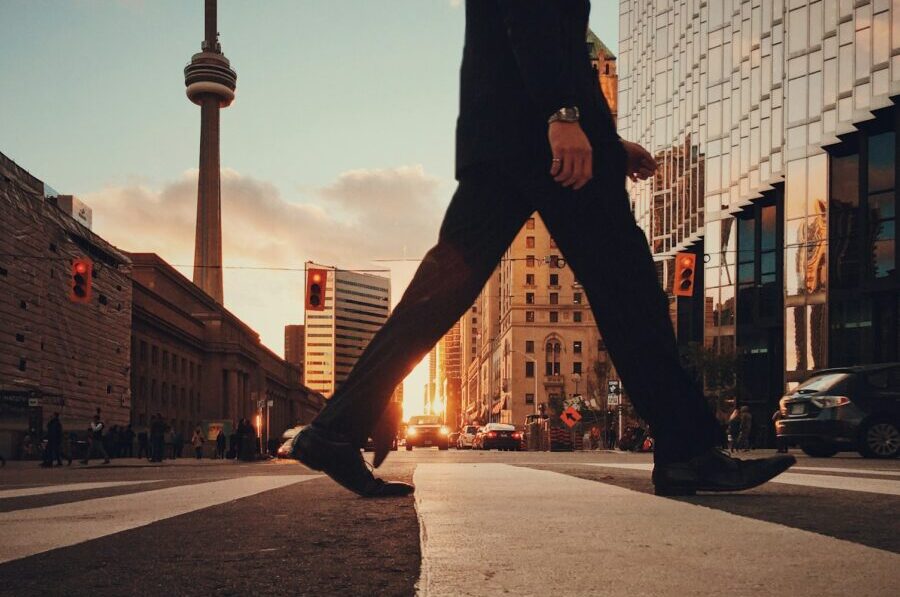 man in dress suit outfit walking in front of building