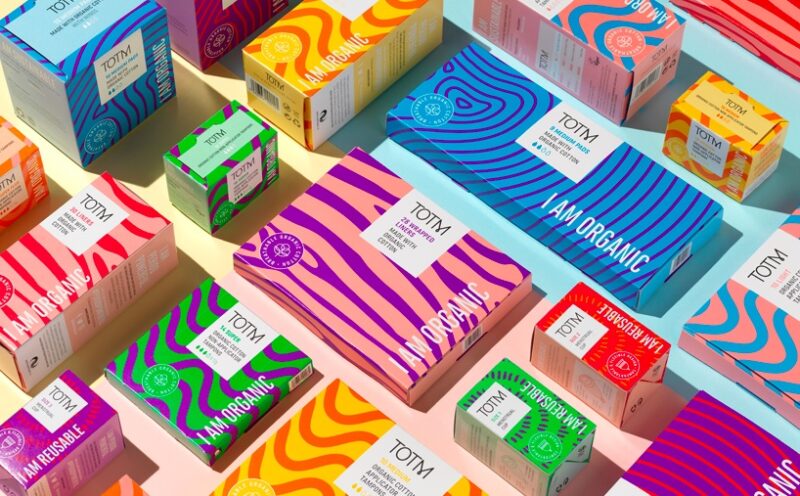 Various boxes of colorful organic period products are artfully arranged on a gradient background, offering a vibrant and sustainable choice.